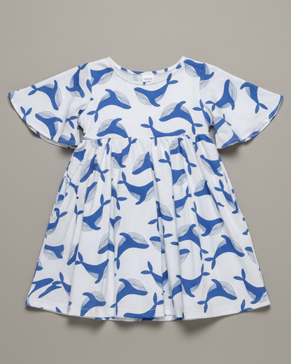 image of the blue whale dress flat-lay on a grey background. A professional studio shoot with a 35mm camera shot at an elevated angle. bright lighting reflecting a premium professinoal product shoot. Highlight the flared sleeves, f