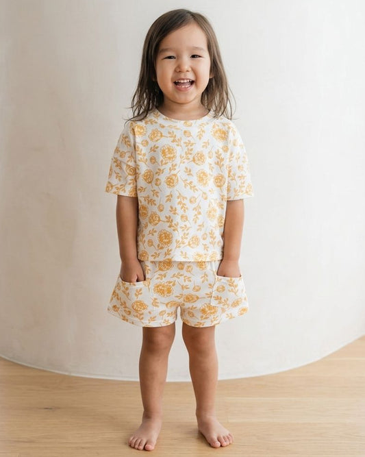 Children's matching t-shirt and shorts set with peony print, made from organic cotton, on a flat white background, showcasing fabric and design details.